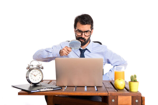 businessman looking at laptop with spy glass
